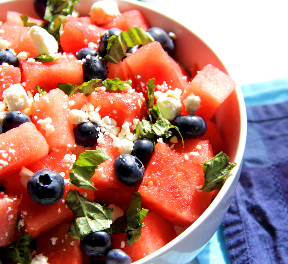 Watermelon salad with feta and blueberries in a large white bowl.