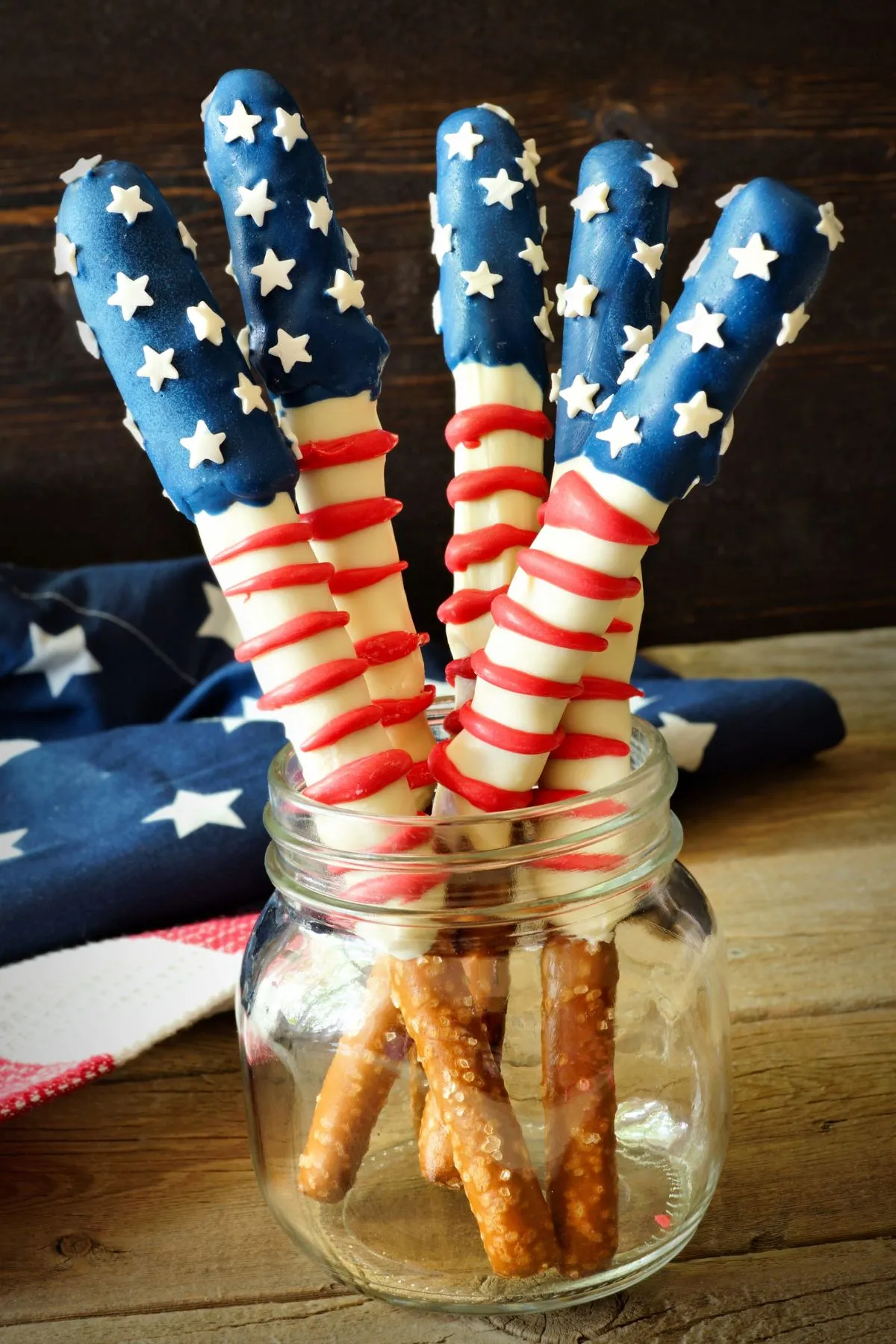 Patriotic pretzel rods in a mason jar in front of an American flag.