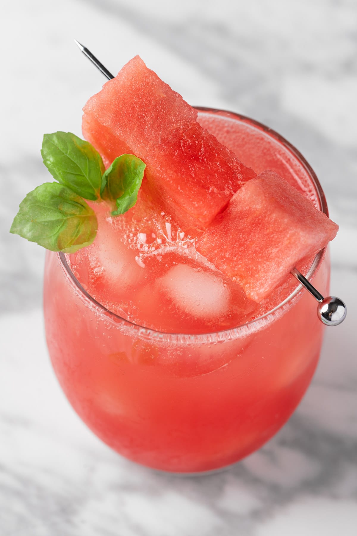 Watermelon basil mocktail in a short glass with basil garnish.