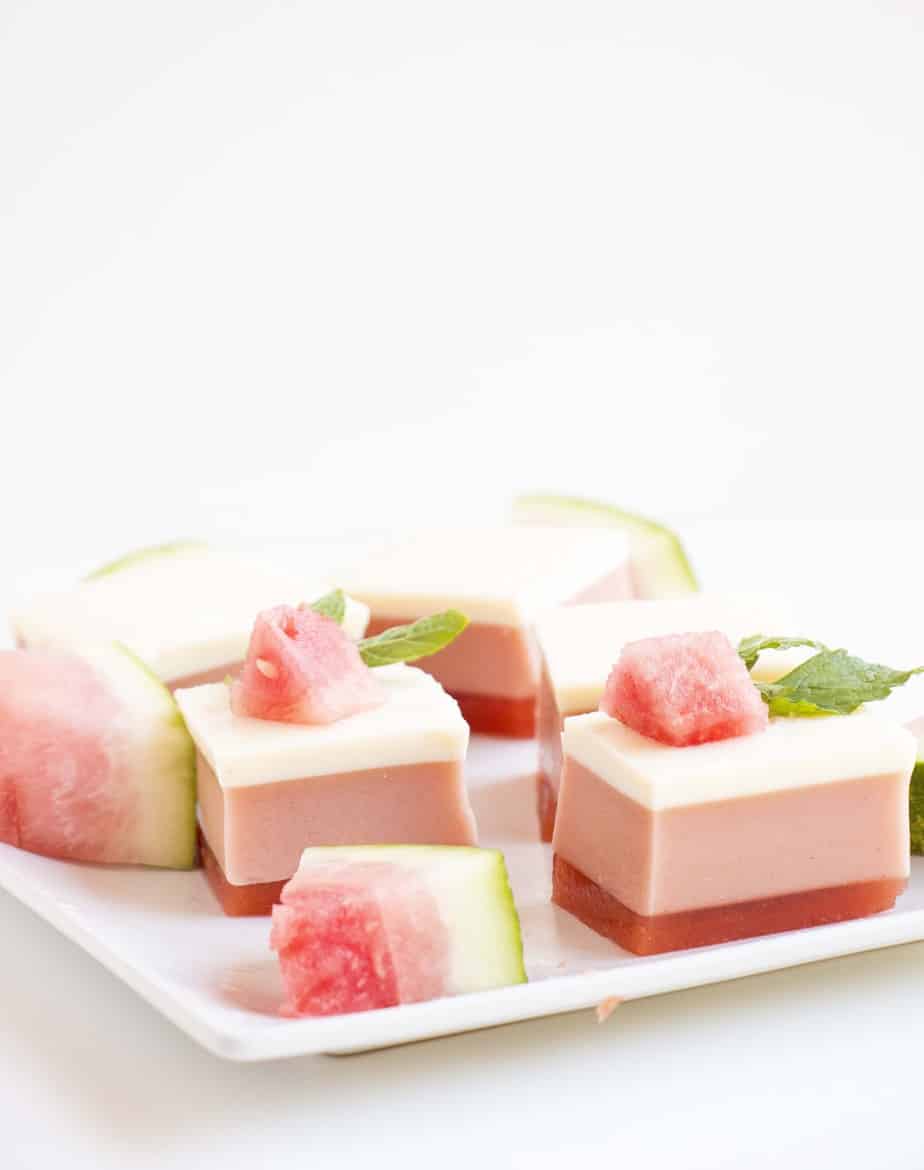 Layered watermelon gelatin cubes on a serving tray with watermelon wedges.