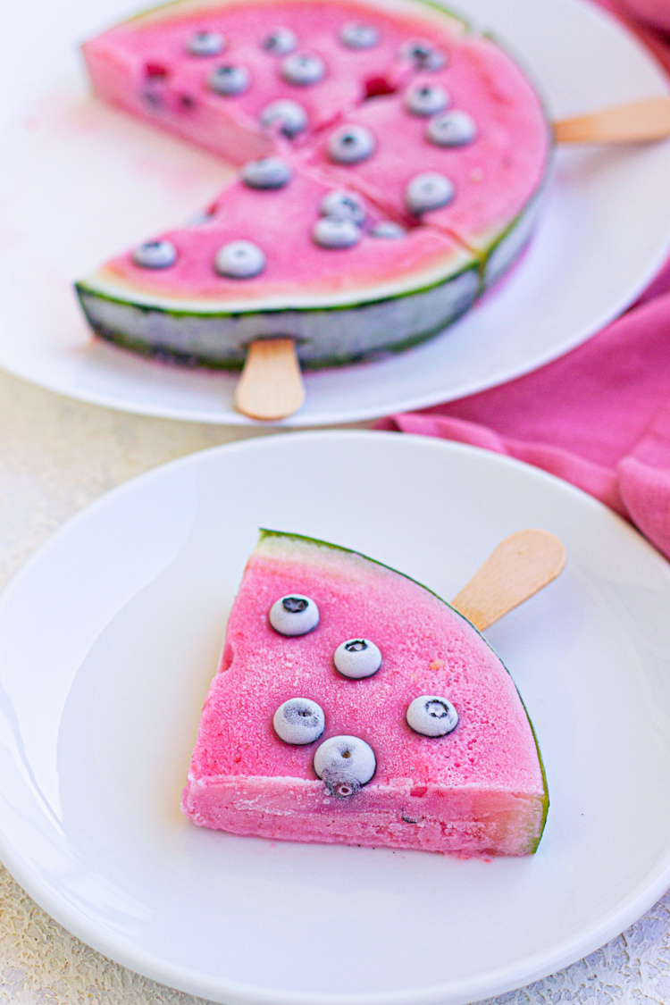 Frozen watermelon yogurt bars with blueberries on a stick.