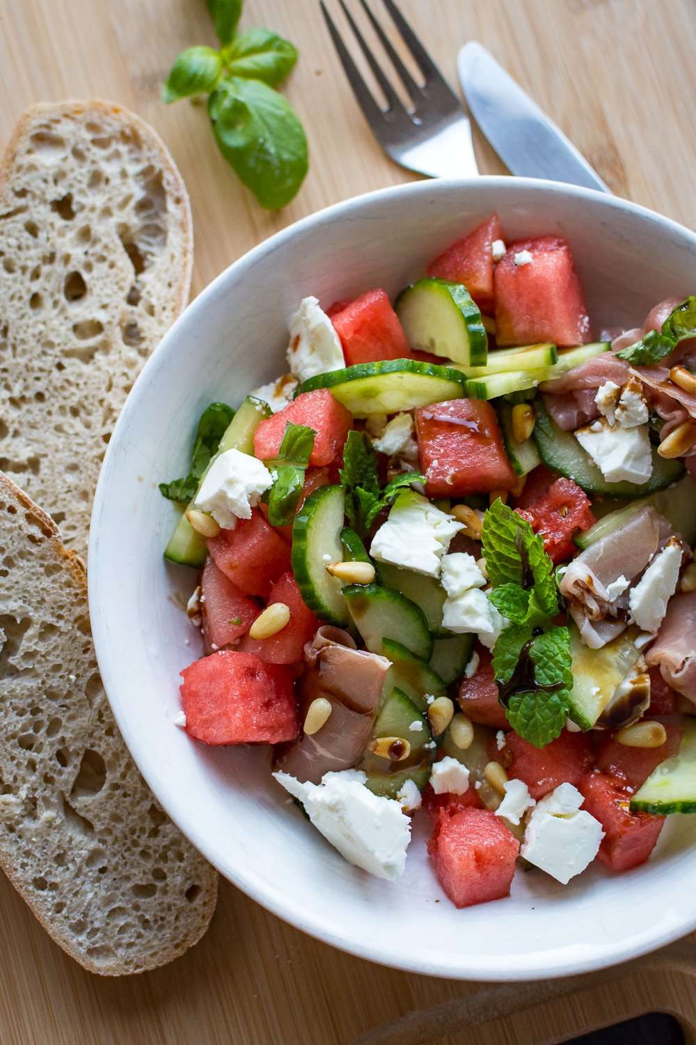 Watermelon salad with feta, pine nuts, cucumber, and prosciutto.