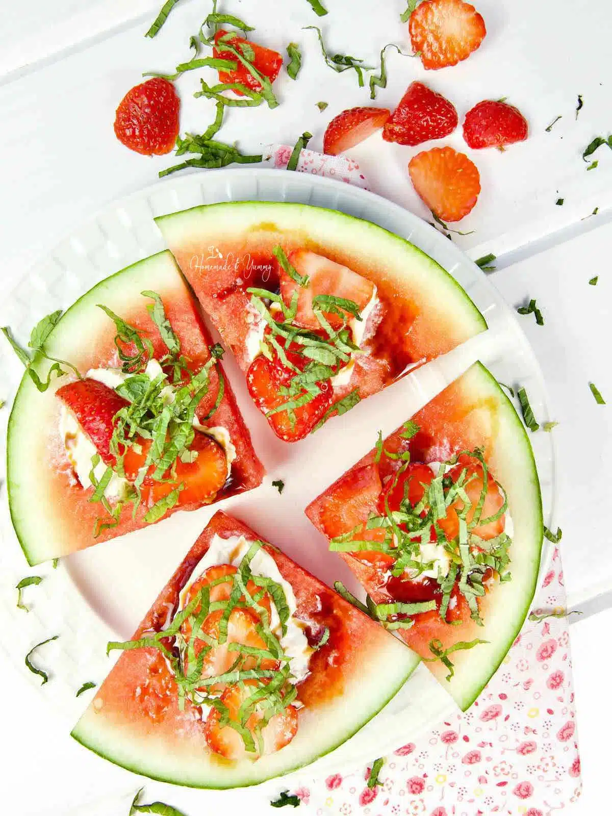 Watermelon fruit pizza dessert with green garnish sprinkled on top.