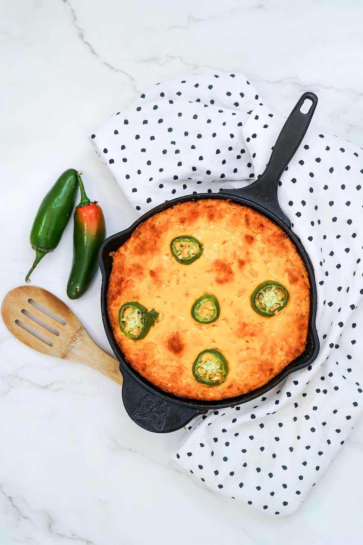 Smoked buffalo chicken dip in a cast iron skillet with jalapenos on top.