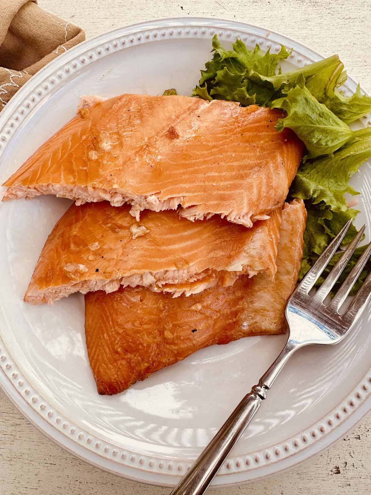 Smoked salmon filets on a white plate with a green salad.
