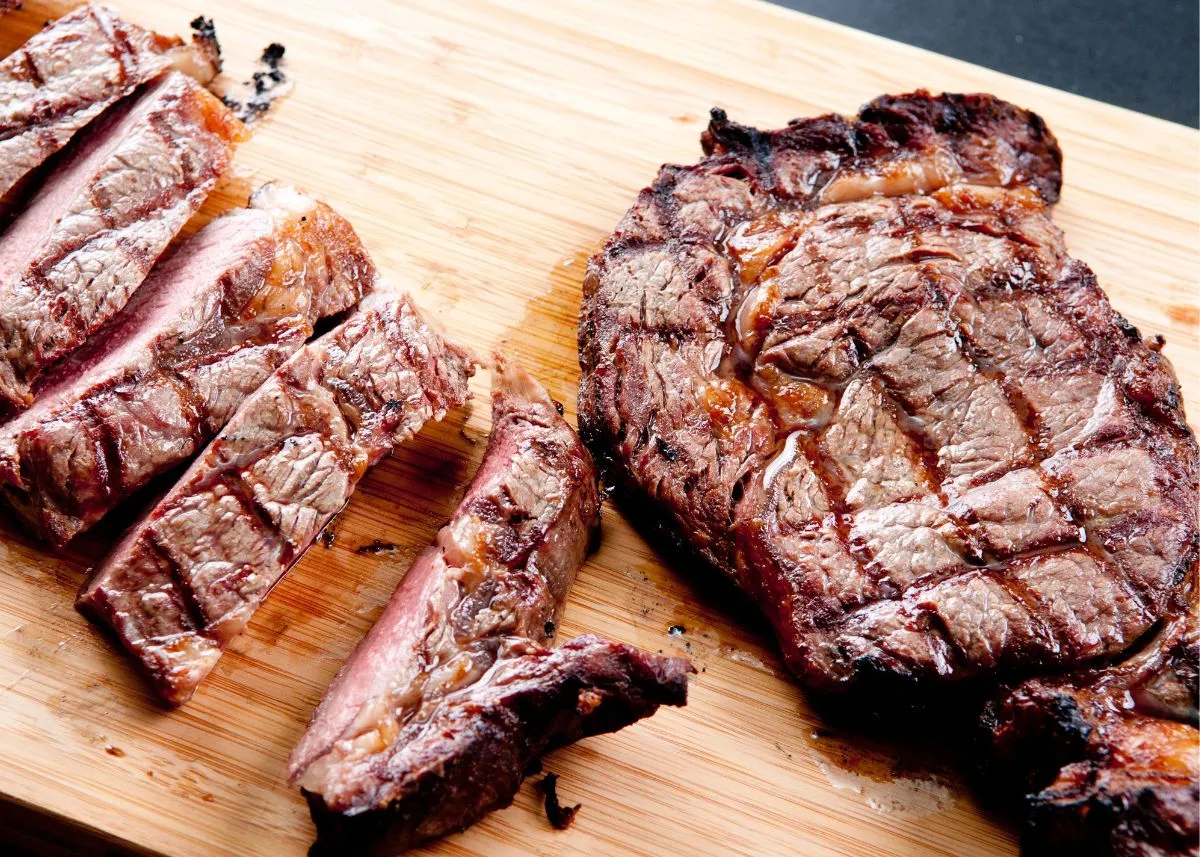 Sliced and whole grilled steaks on a wood cutting board.