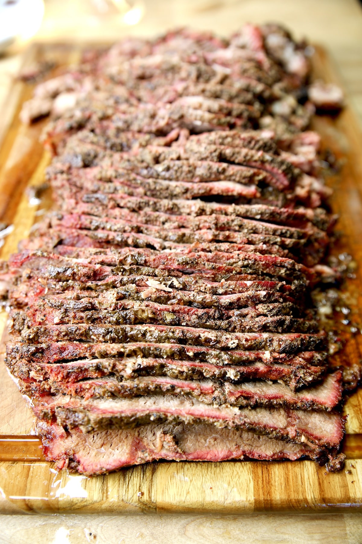 Thinly sliced smoked beef on a wooden cutting board.