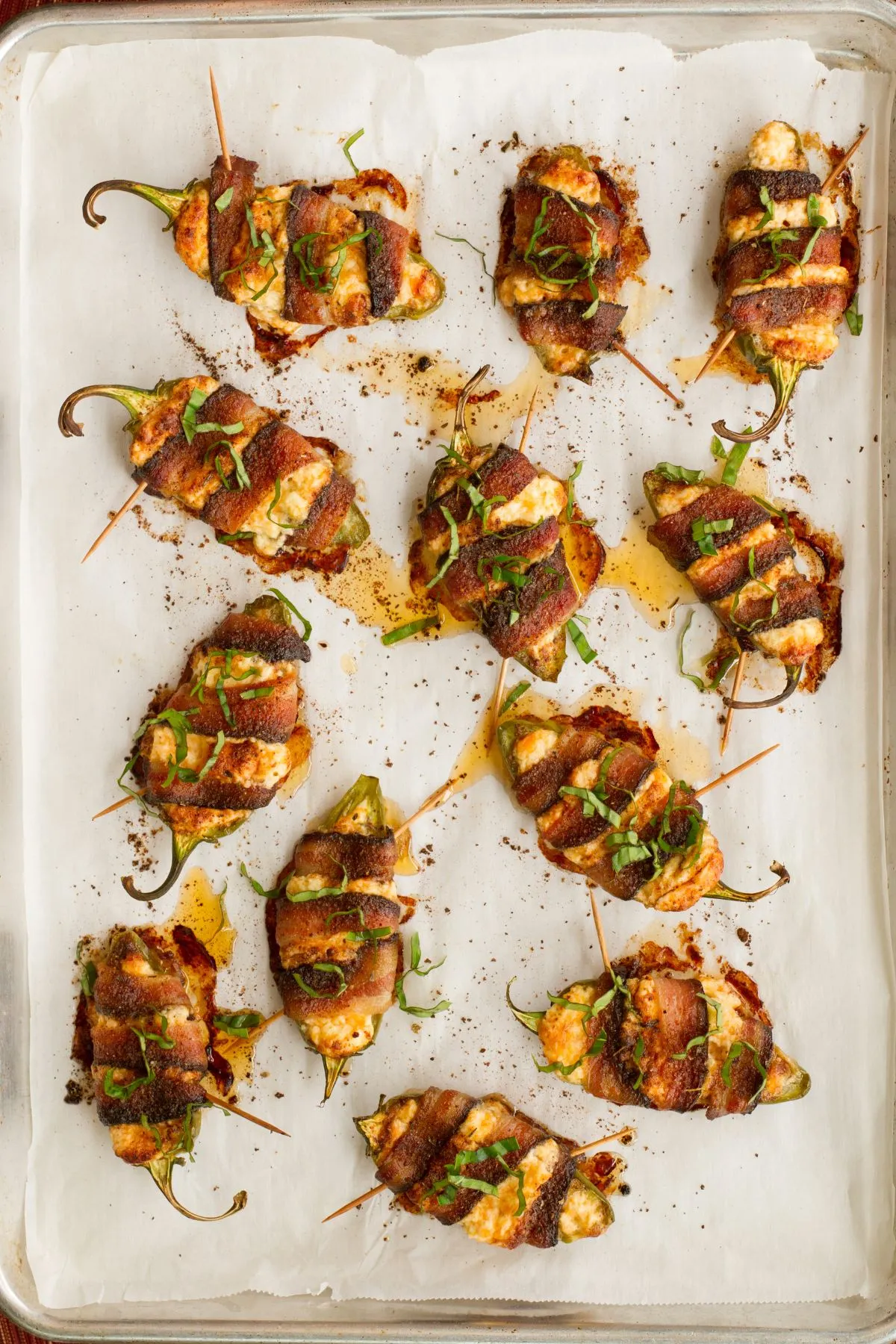 Smoked jalapeno poppers with cheese and bacon on a parchment-lined baking sheet.