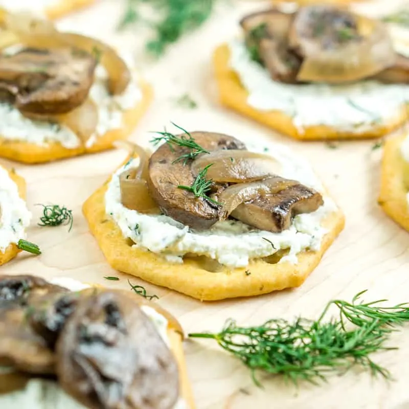Crackers with cheese spread and truffle mushrooms on top.