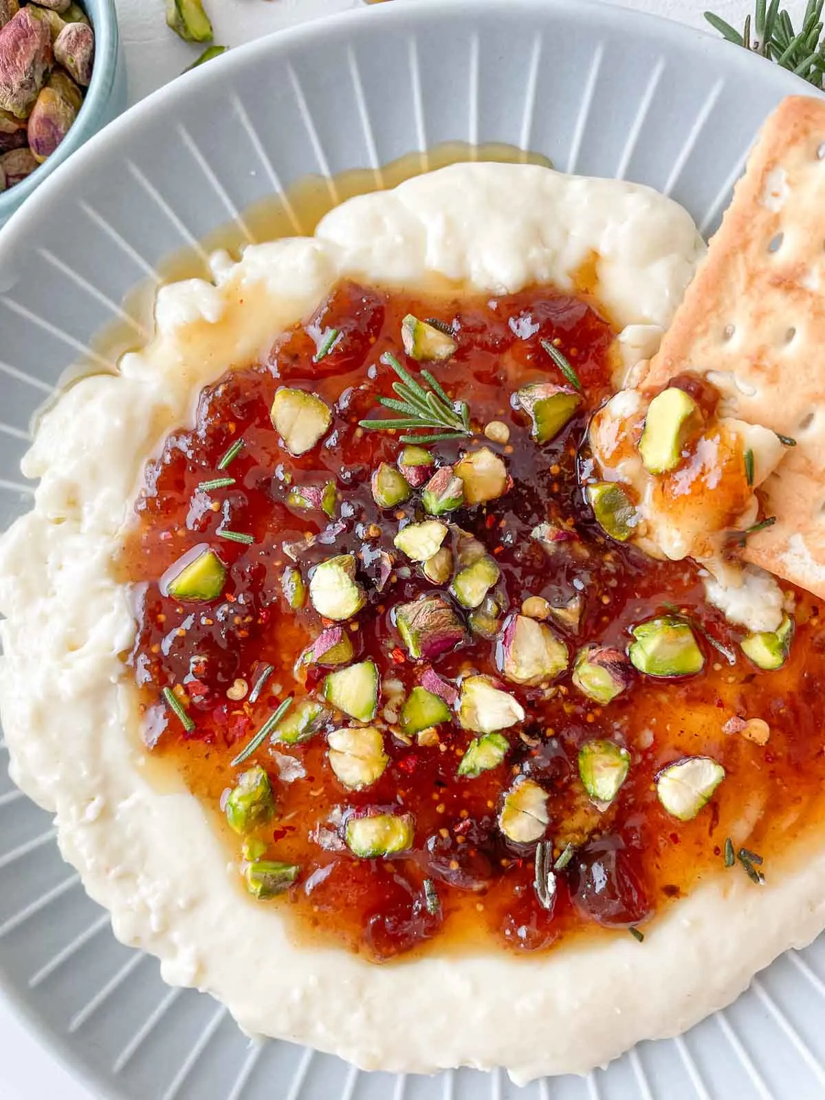 Whipped brie with crushed nuts and chili sauce on top with crackers.