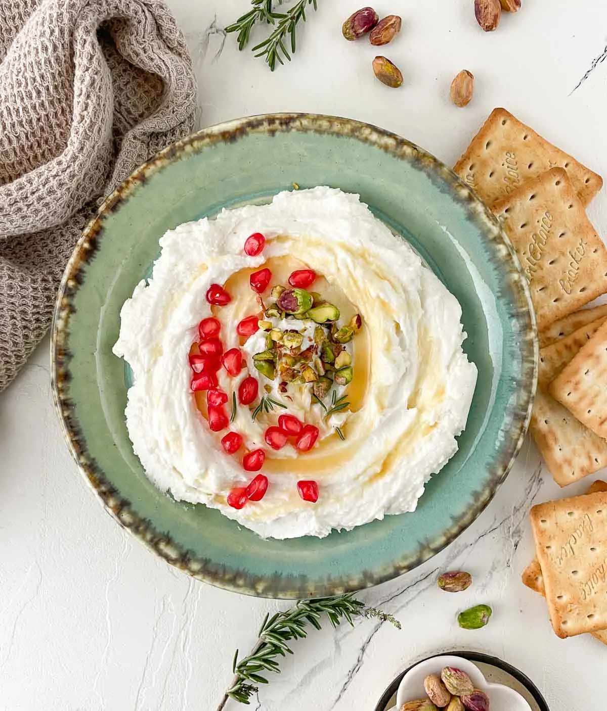 Whipped goat cheese with honey and pomegranates on top with crackers.