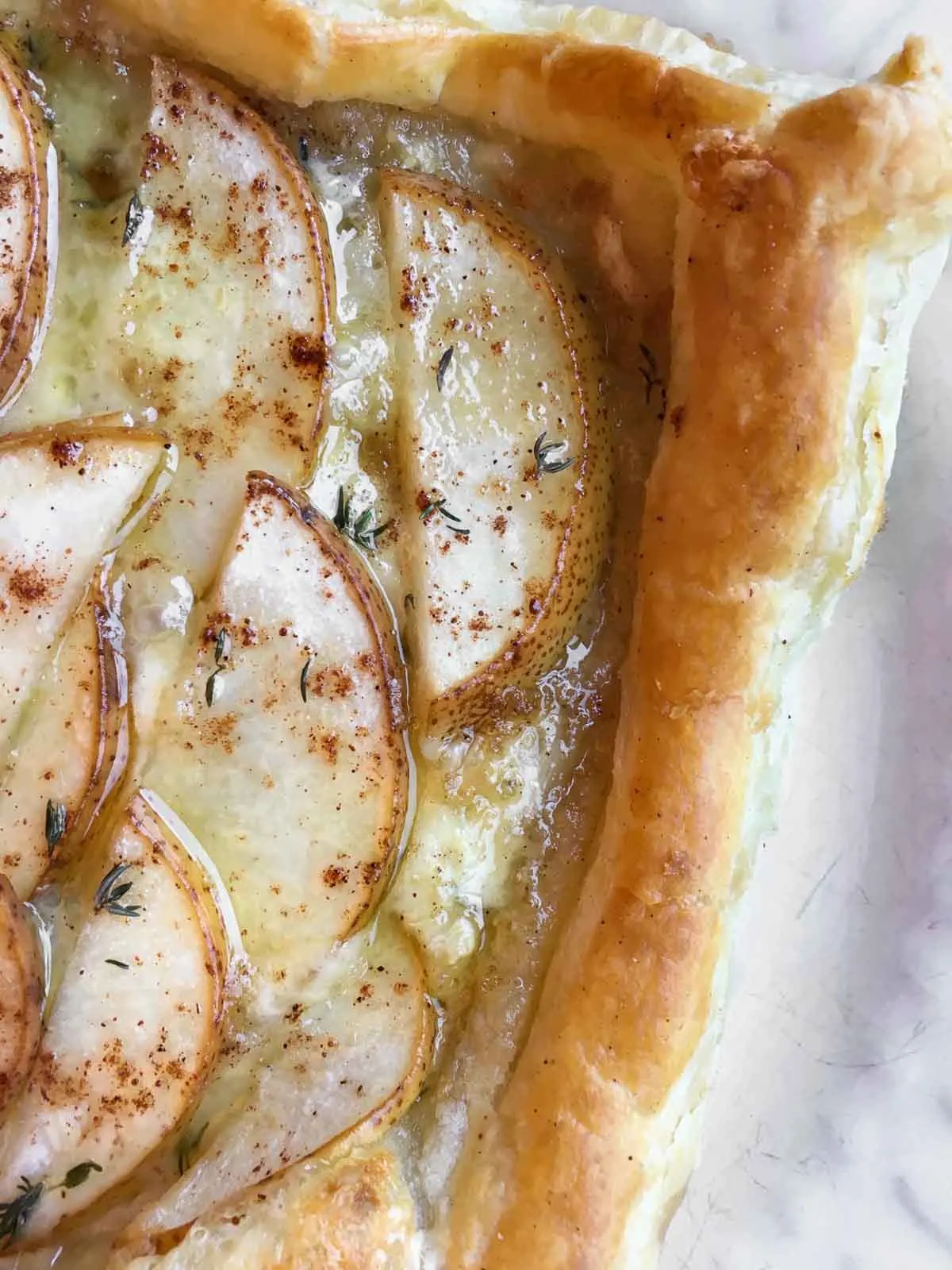 Brie and Pear puff pastry appetizer with green garnish.