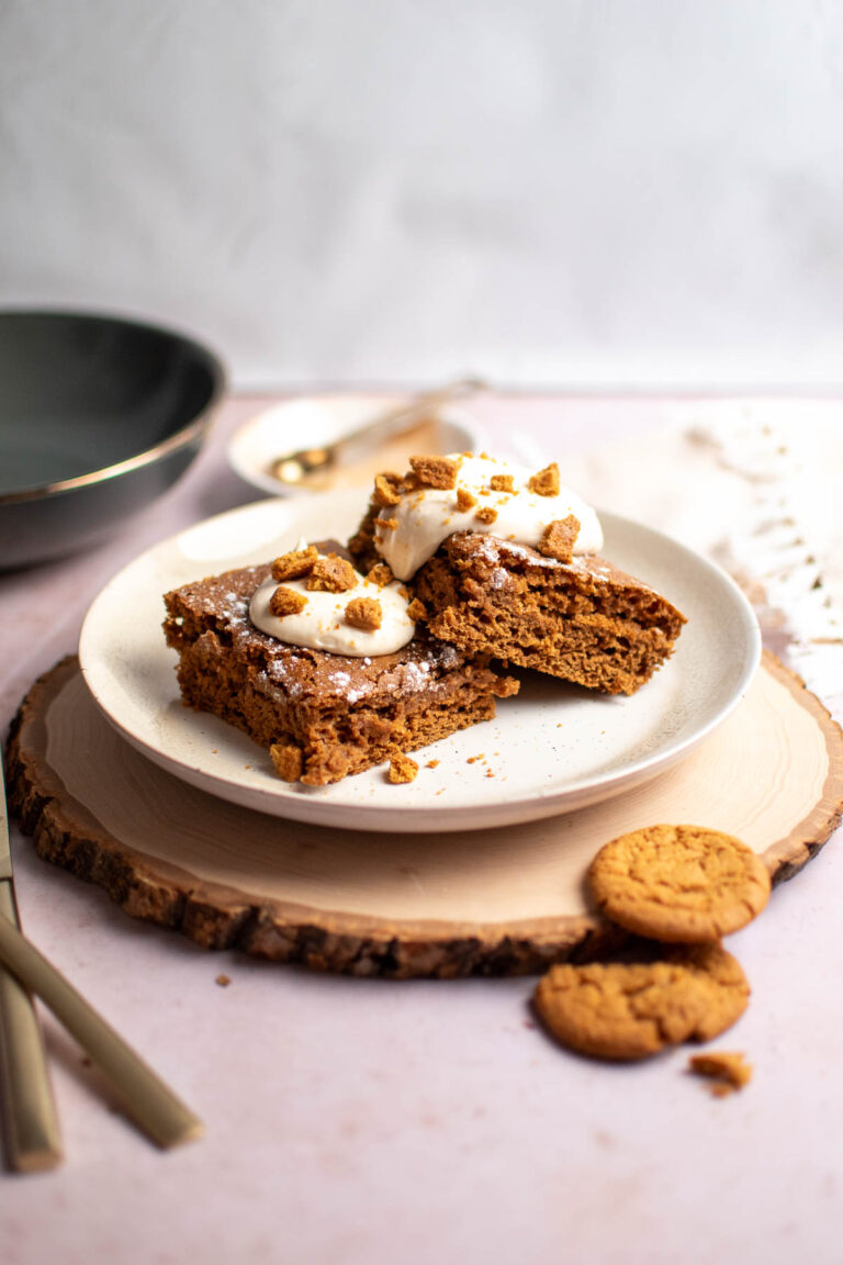 Two pieces of gingerbread pancake bake on plate with ginger snap cookies nearby.