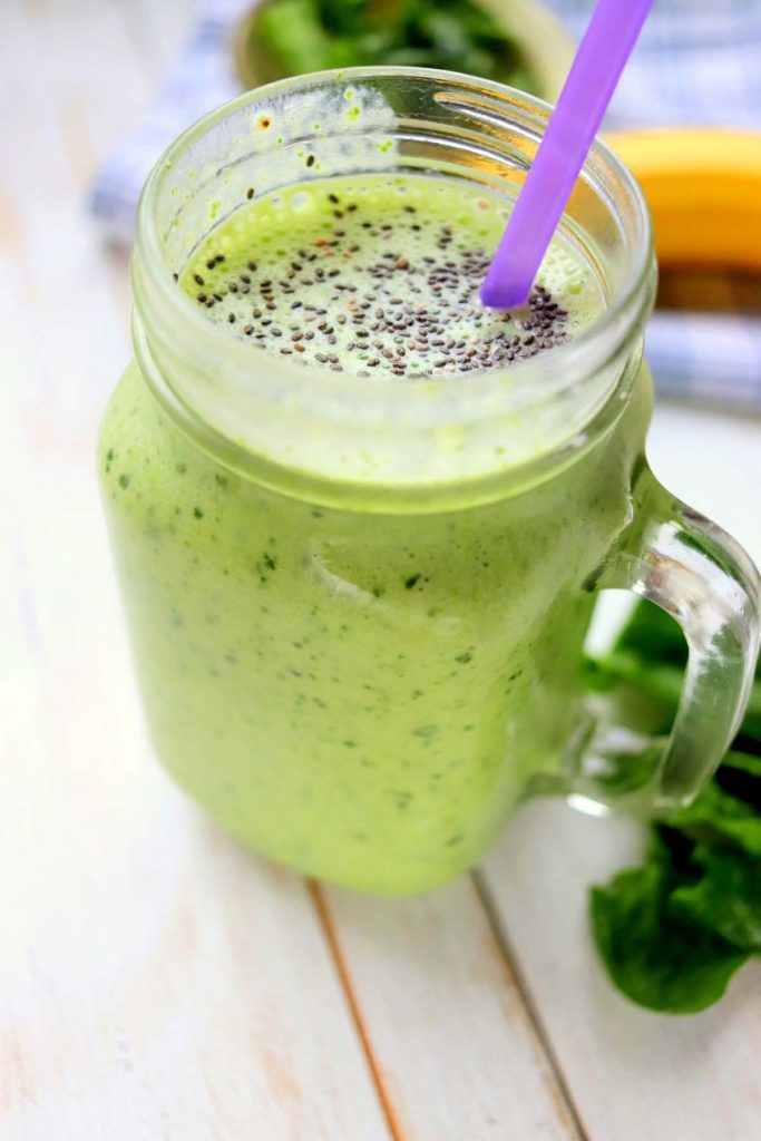 Green smoothie with chia seeds and a purple straw.