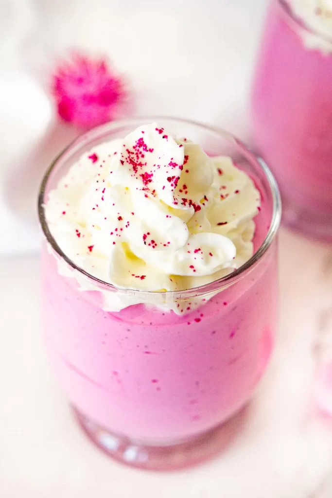 A pink cottage cheese smoothie with whipped cream on top.