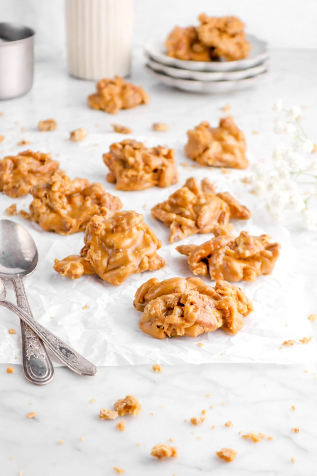 Southern pralines on white parchment paper next to two silver spoons.