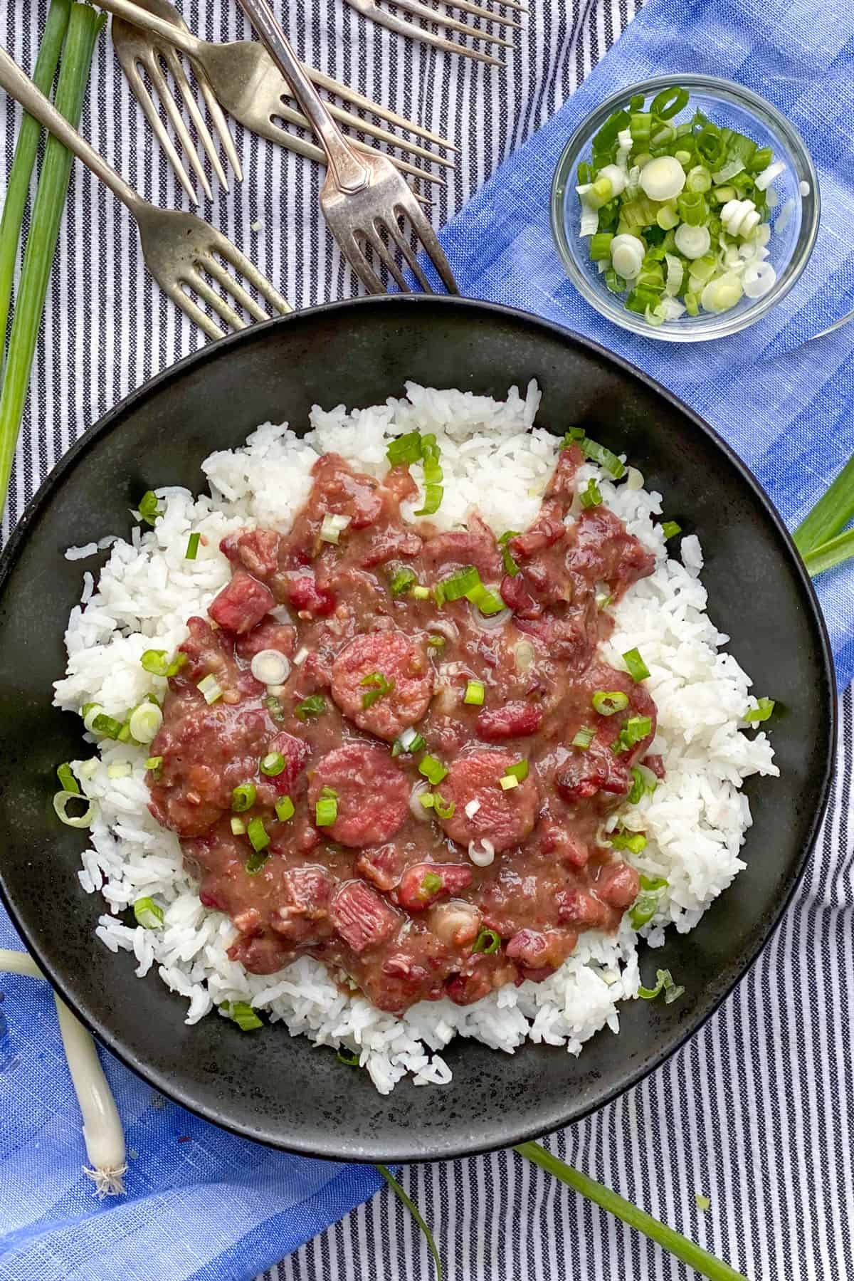 Red beans and rice in a black bowl with green garnish.