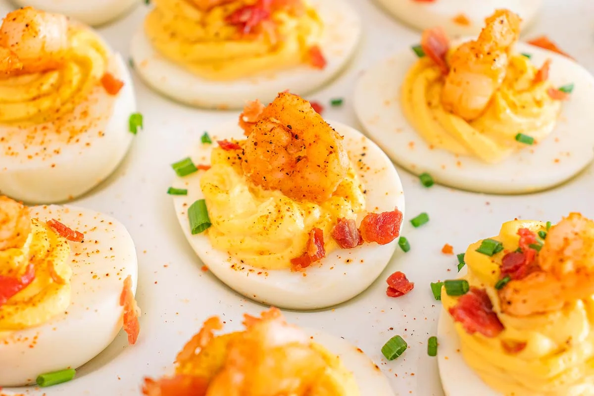 Cajun deviled eggs with green garnish on a white background,