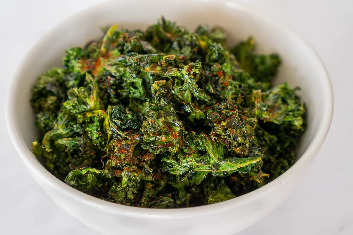 Cajun kale chips in a large white bowl.