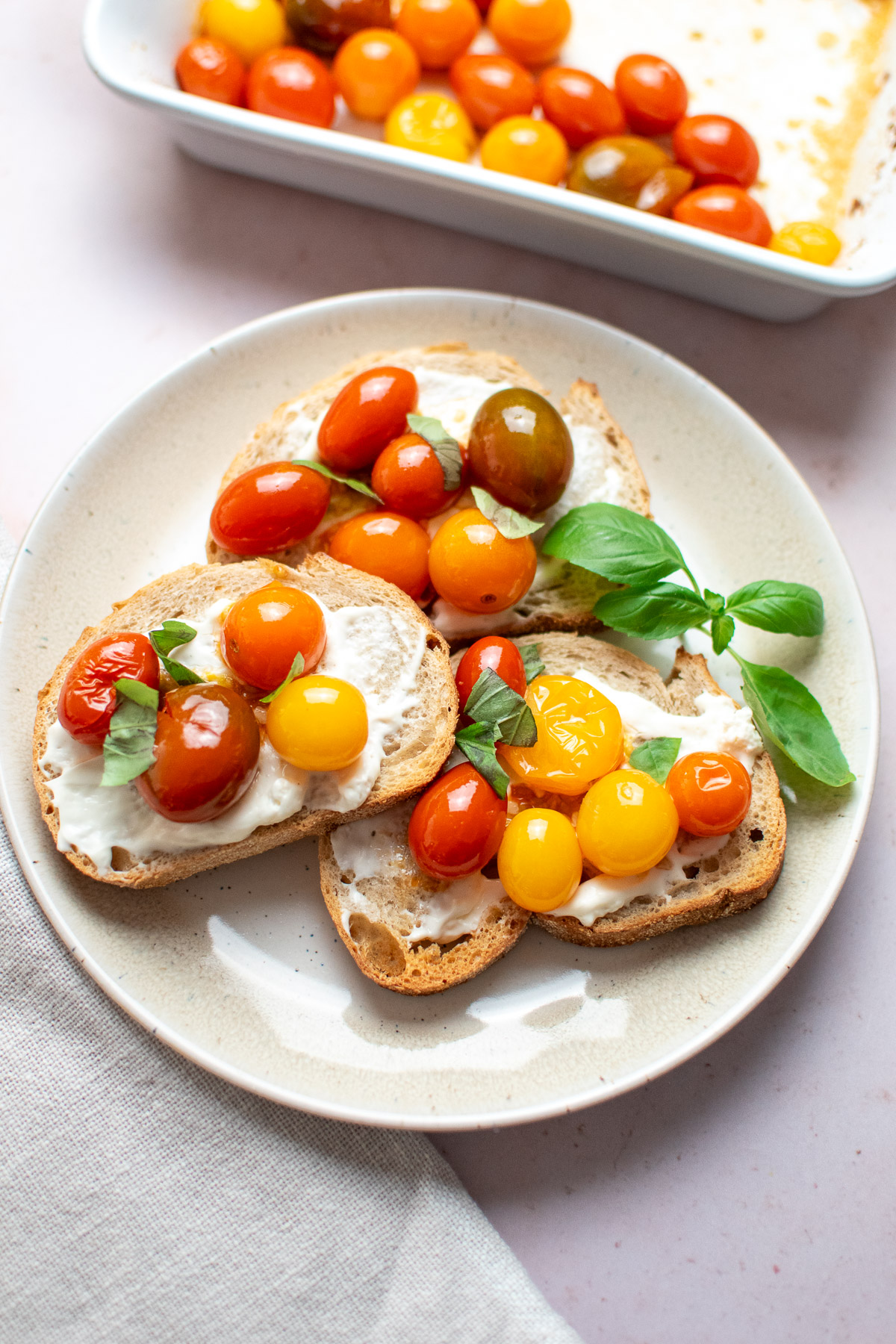 Toast appetizer with roasted tomatoes, cream cheese, and basil.