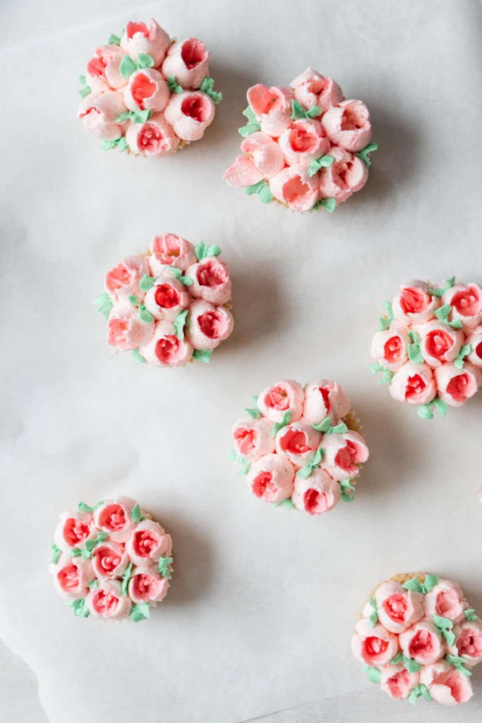Vanilla cupcakes with piped frosting spring flowers on top.