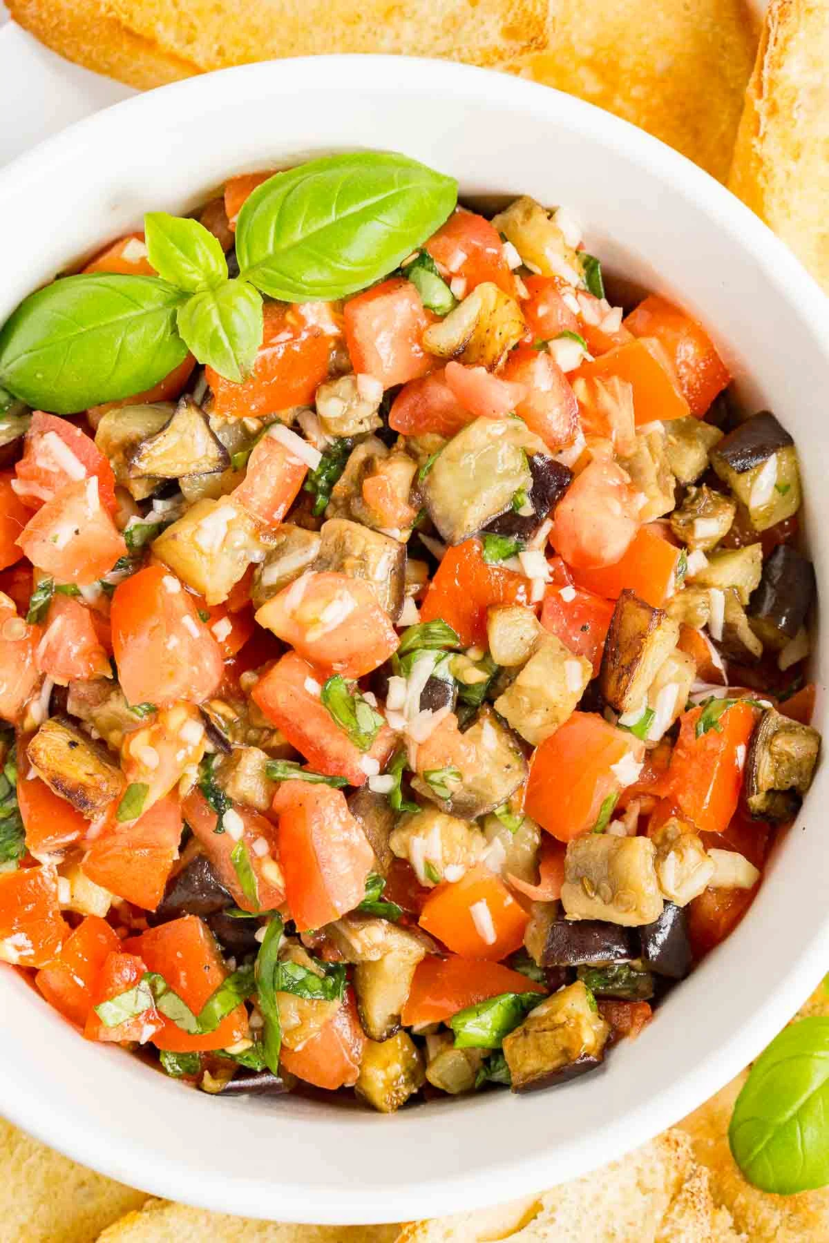 Eggplant bruschetta in a white bowl with green garnish.