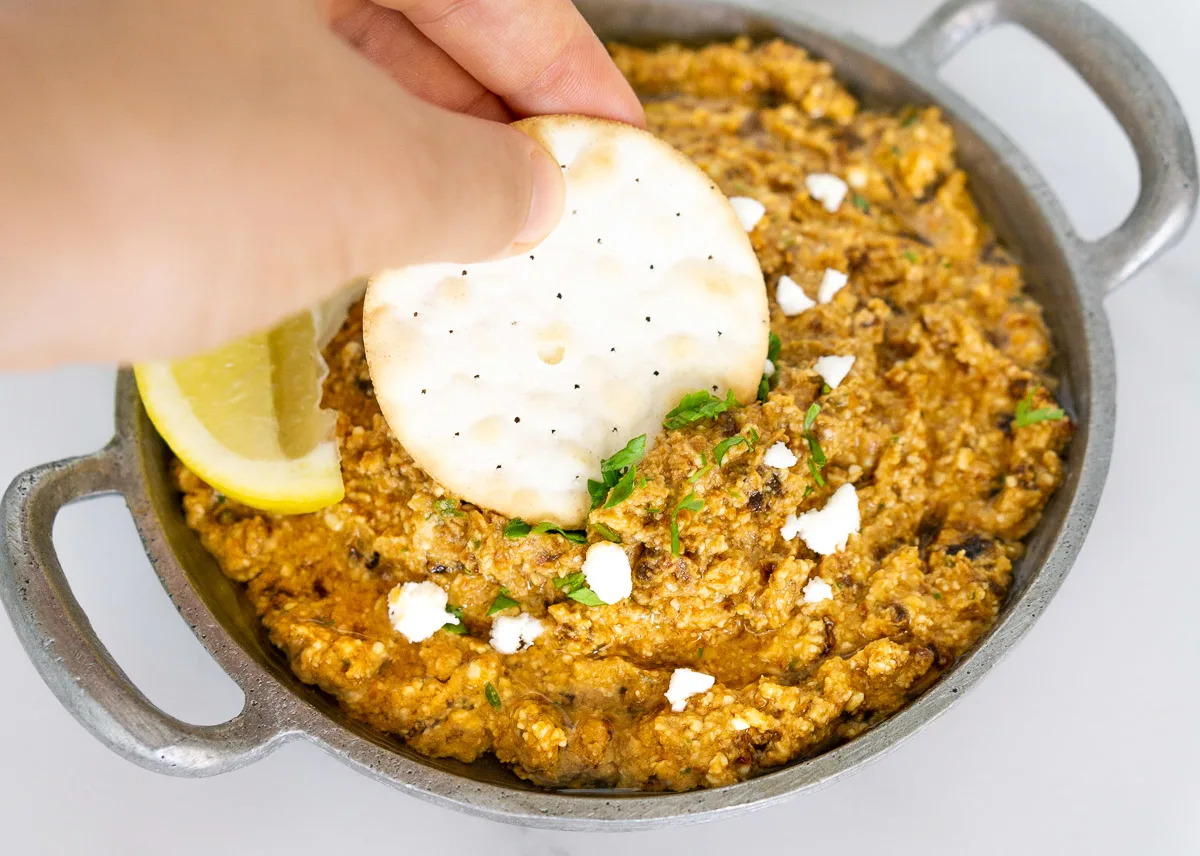 Sundried tomato feta dip with a lemon wedge and cracker.