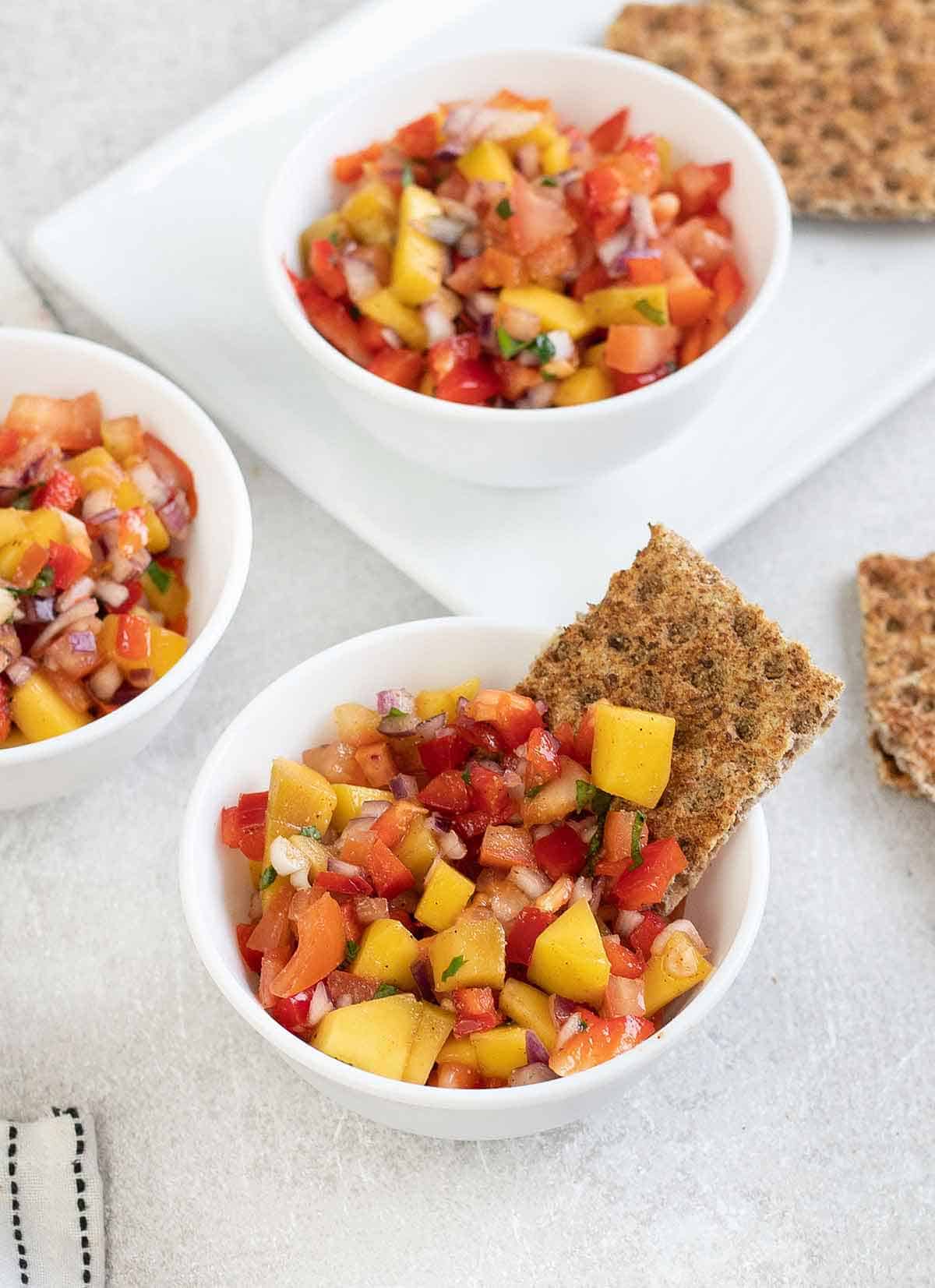 Chunky habanero salsa in white bowls with rustic crackers.