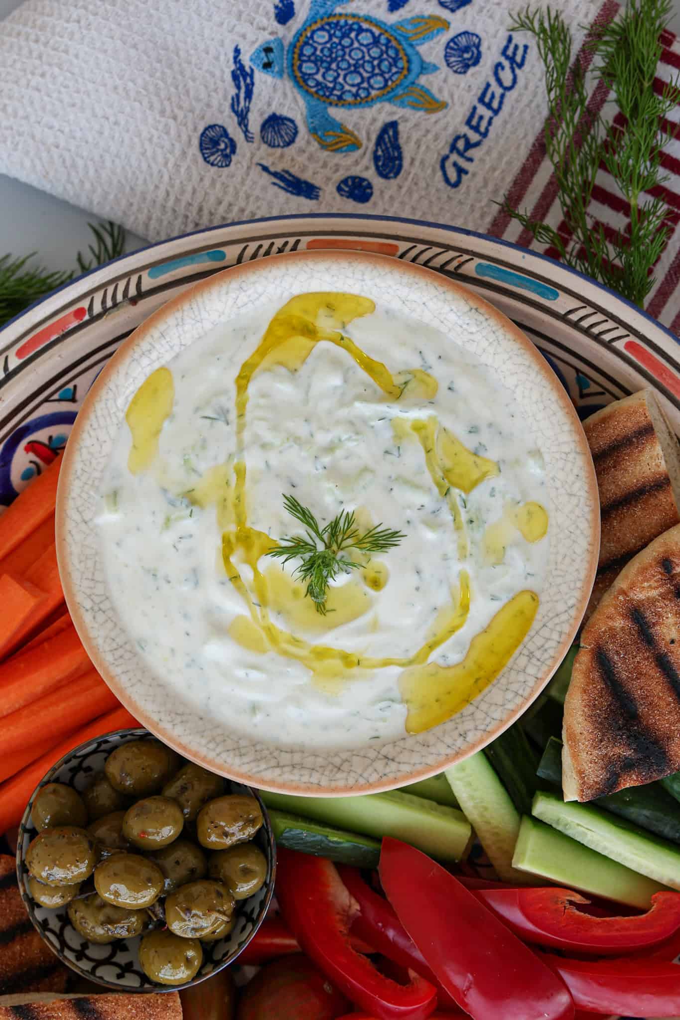 Tzatziki sauce in a bowl, surrounded by veggies.