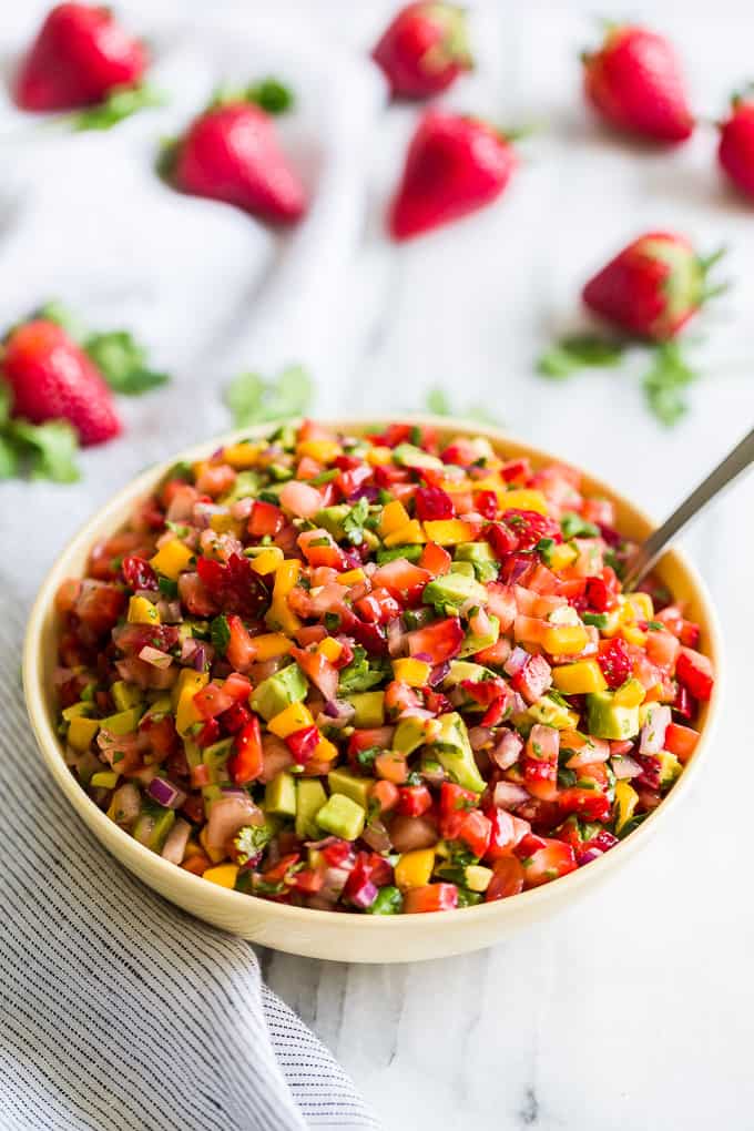 Strawberry mango avocado salsa in a bowl with a spoon.