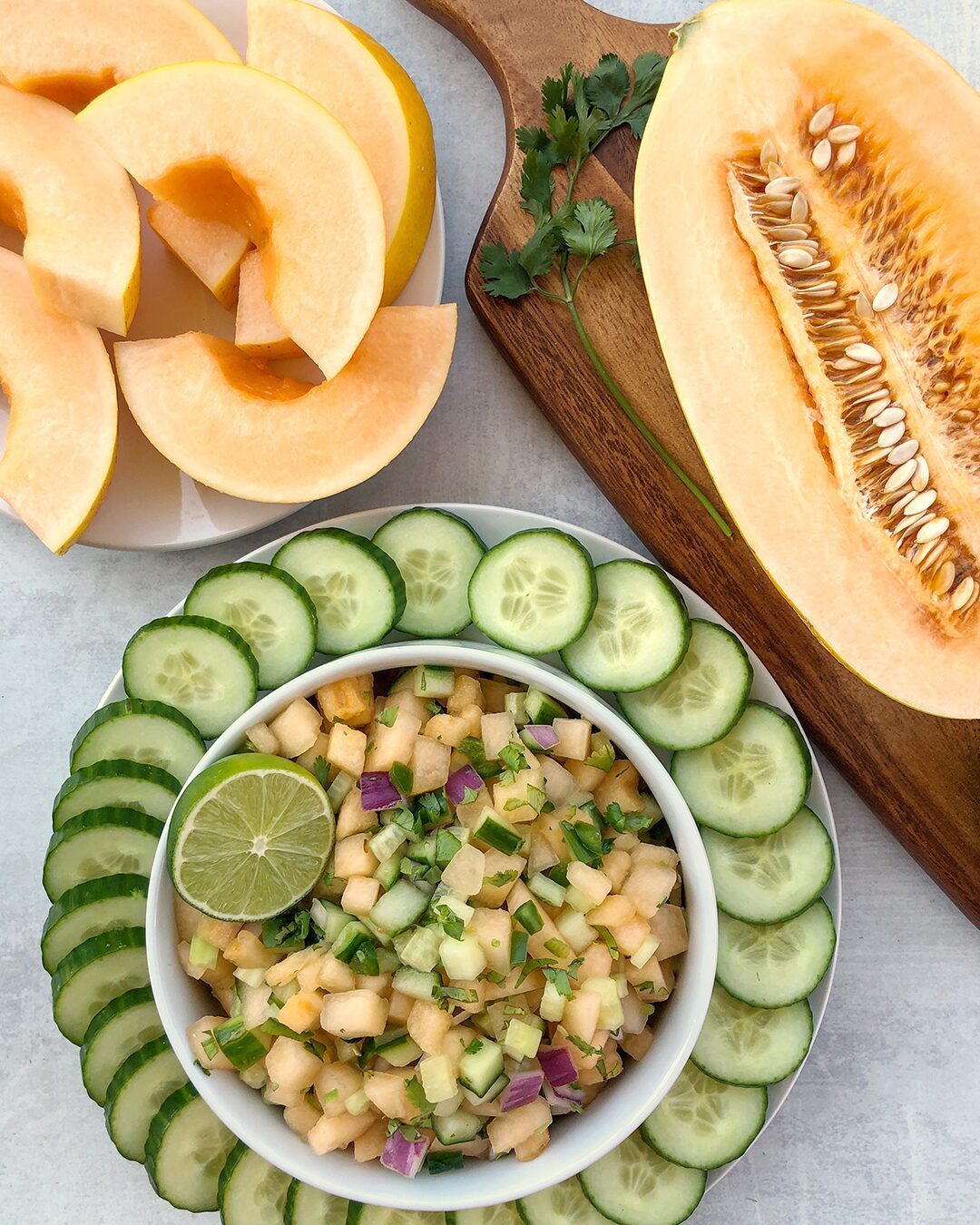 Melon cucumber salsa in a bowl surrounded by sliced cucumbers.