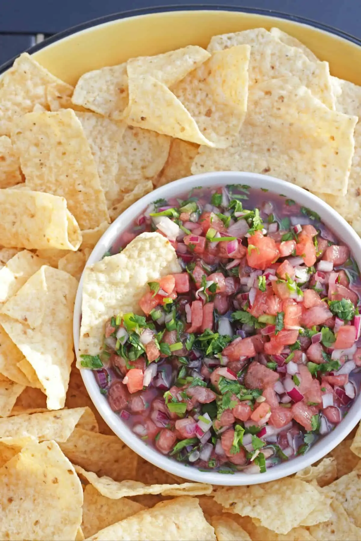 Watermelon salsa in a white bowl surrounded by tortilla chips.