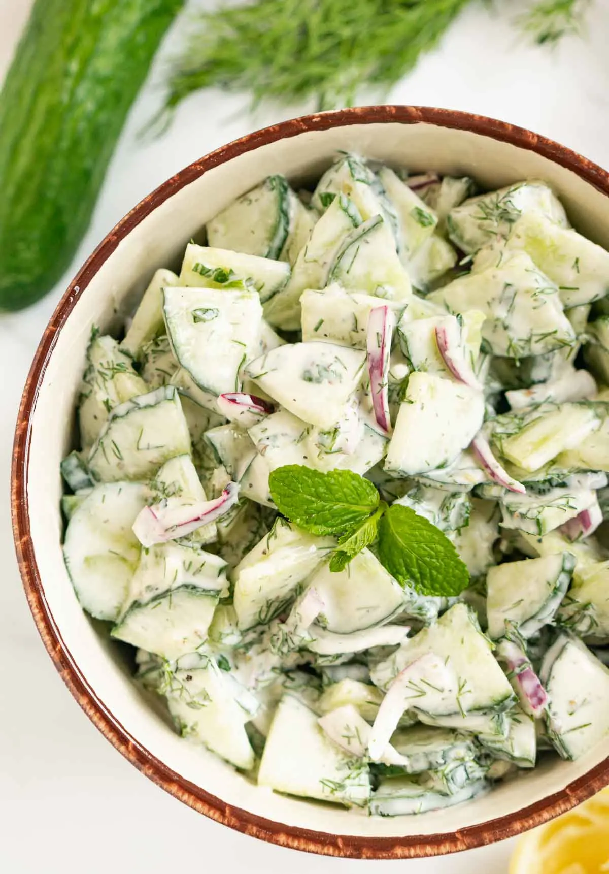Creamy tzatziki cucumber salad in a bowl with green garnish.