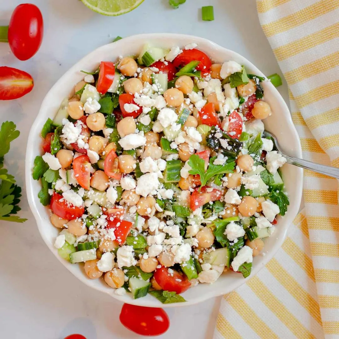 Summer chickpea salad with tomatoes and feta in a white bowl.