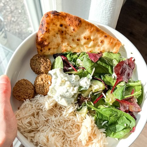 Falafel mediterranean bowl with rice, greens, naan bread, and tzatziki sauce.
