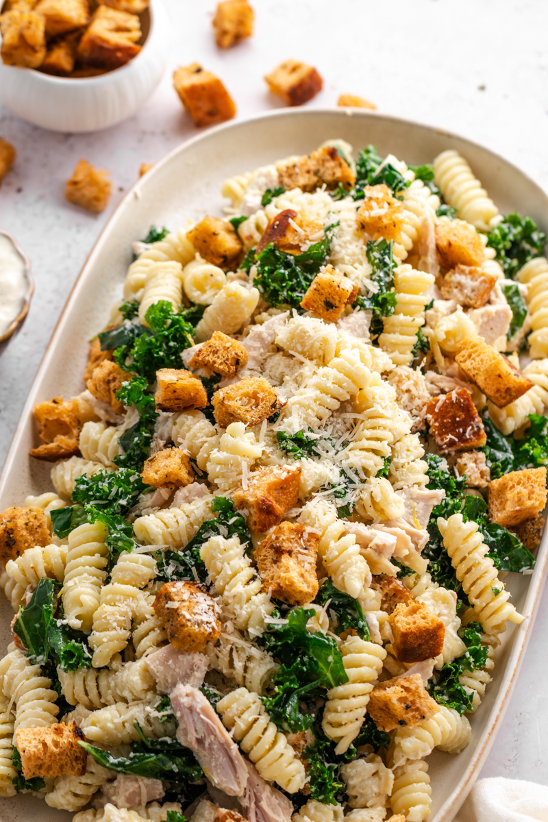 Chicken Caesar salad with rotini pasta, lettuce, croutons, and shredded cheese/