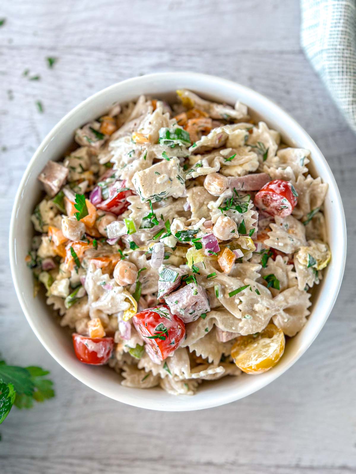 Pasta salad with chicken, bacon, and ham in a large white bowl.