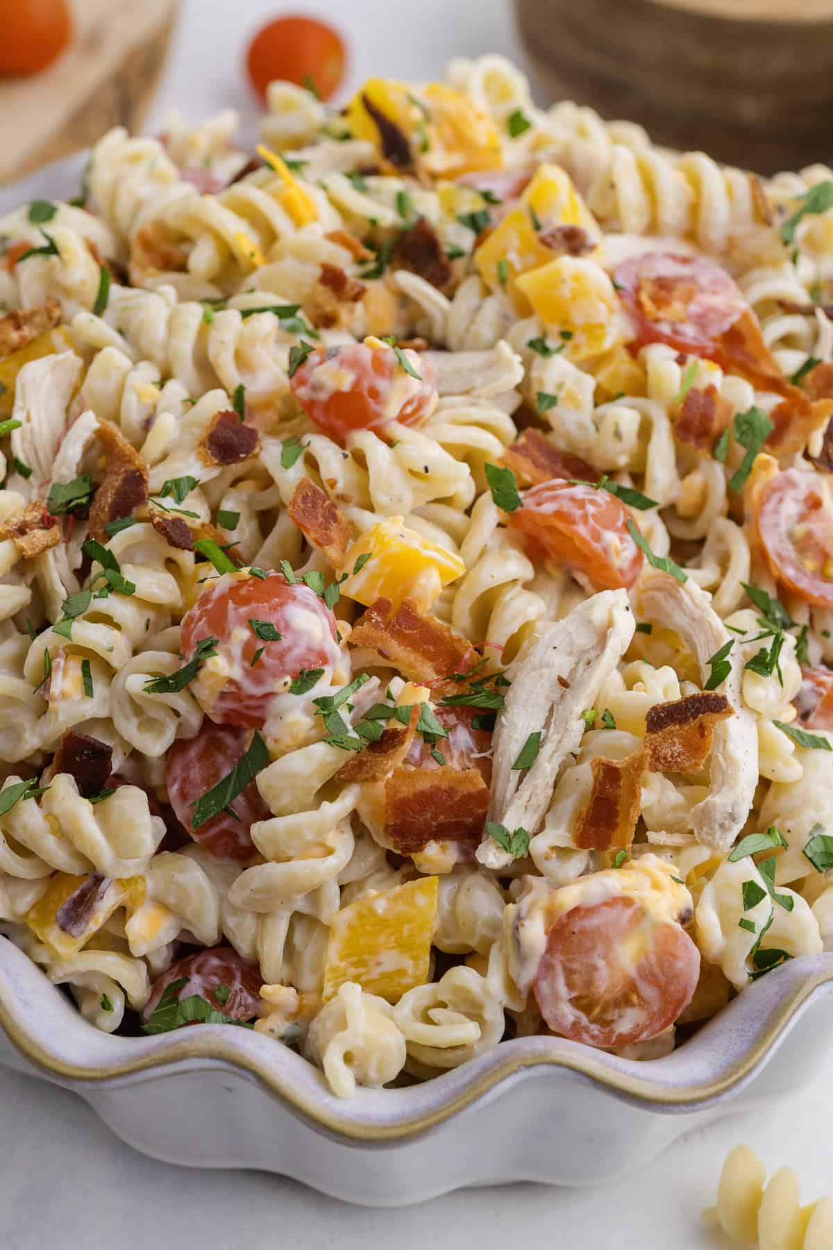 Chicken ranch pasta salad with bacon in a wavy decorative bowl.