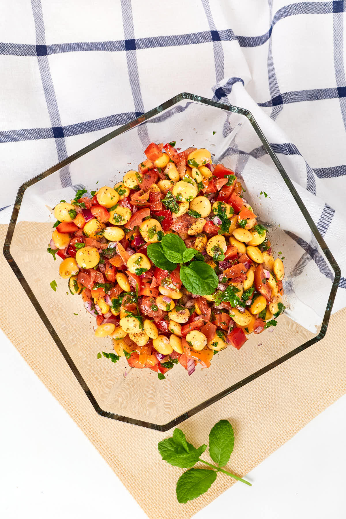 Lupini bean salad in a clear geometric bowl with corn and tomatoes.
