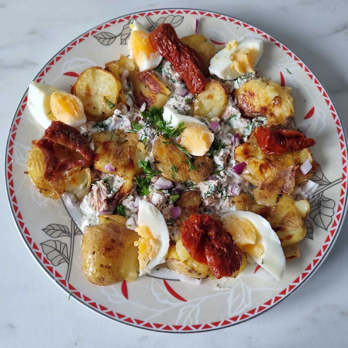 Bacon and egg potato salad on a round plate on a kitchen counter.