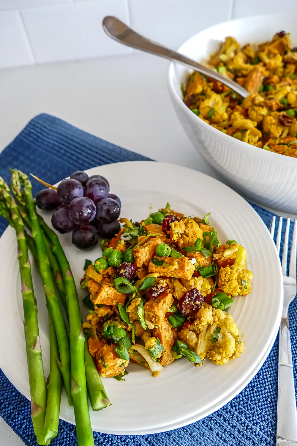 Sweet potato cauliflower salad with curry spices and cranberries on a white plate.