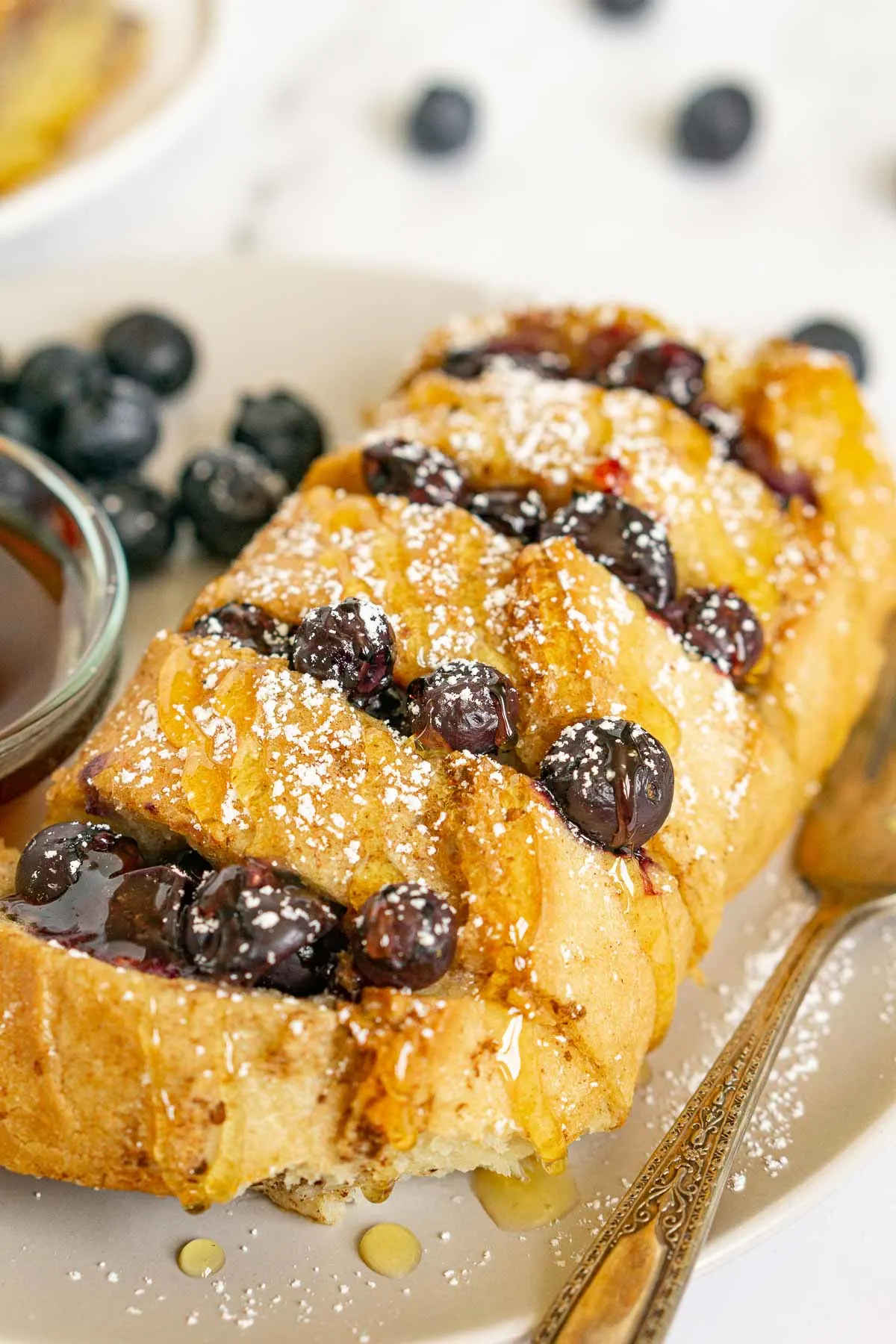 Hasselback stuffed French toast with blueberries and powdered sugar on top.