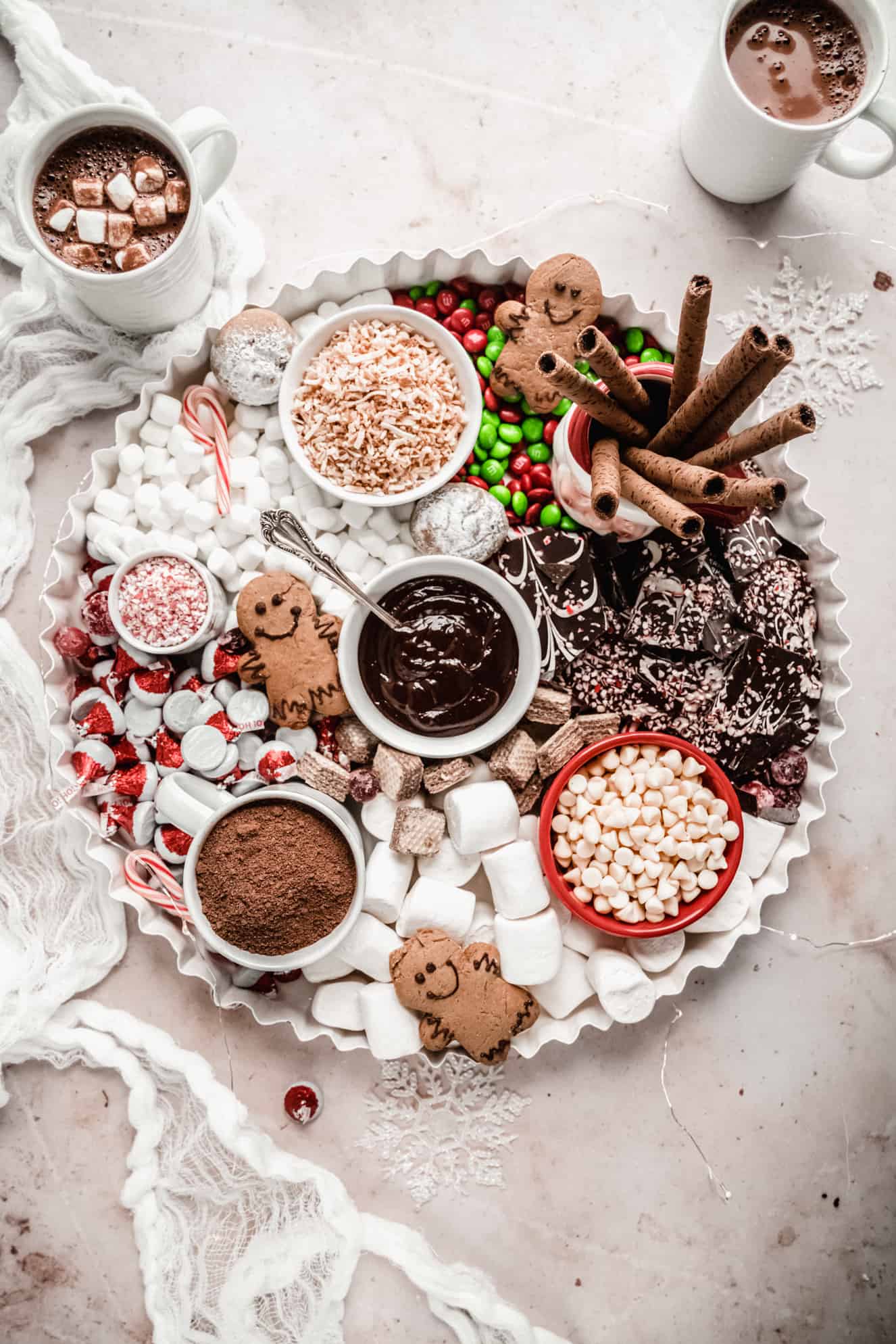 A hot chocolate charcuterie board with peppermint desserts, chocolates, and marshmallows.