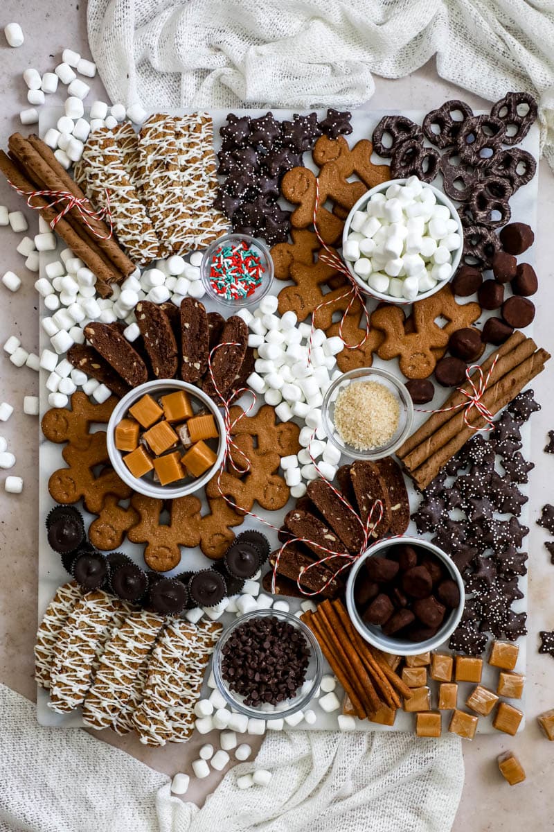 A hot chocolate charcuterie board with cookies, chocolates, caramels, and marshmallows.
