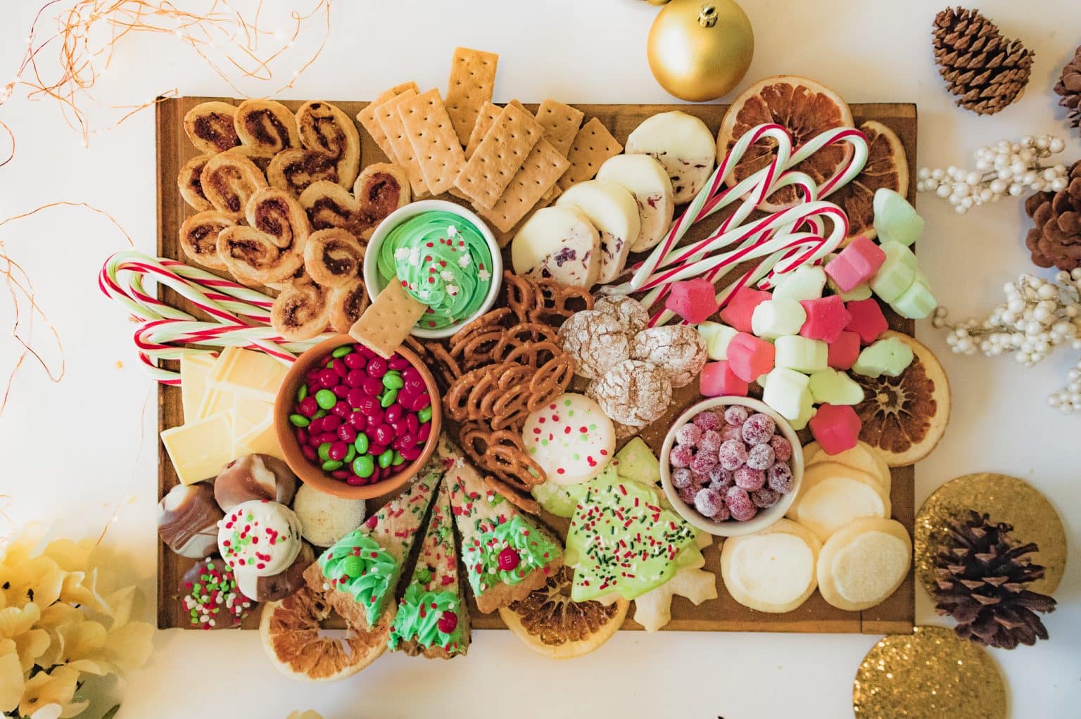 A Christmas dessert charcuterie board with dessert dip, pretzels, crackers, cookies, and candy.