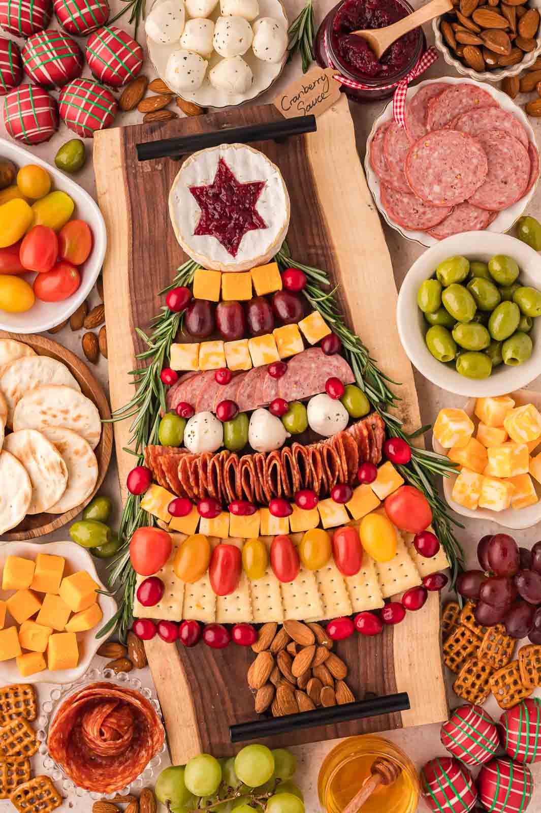 A Christmas tree-shaped charcuterie spread with veggies, meat, cheese, and crackers.