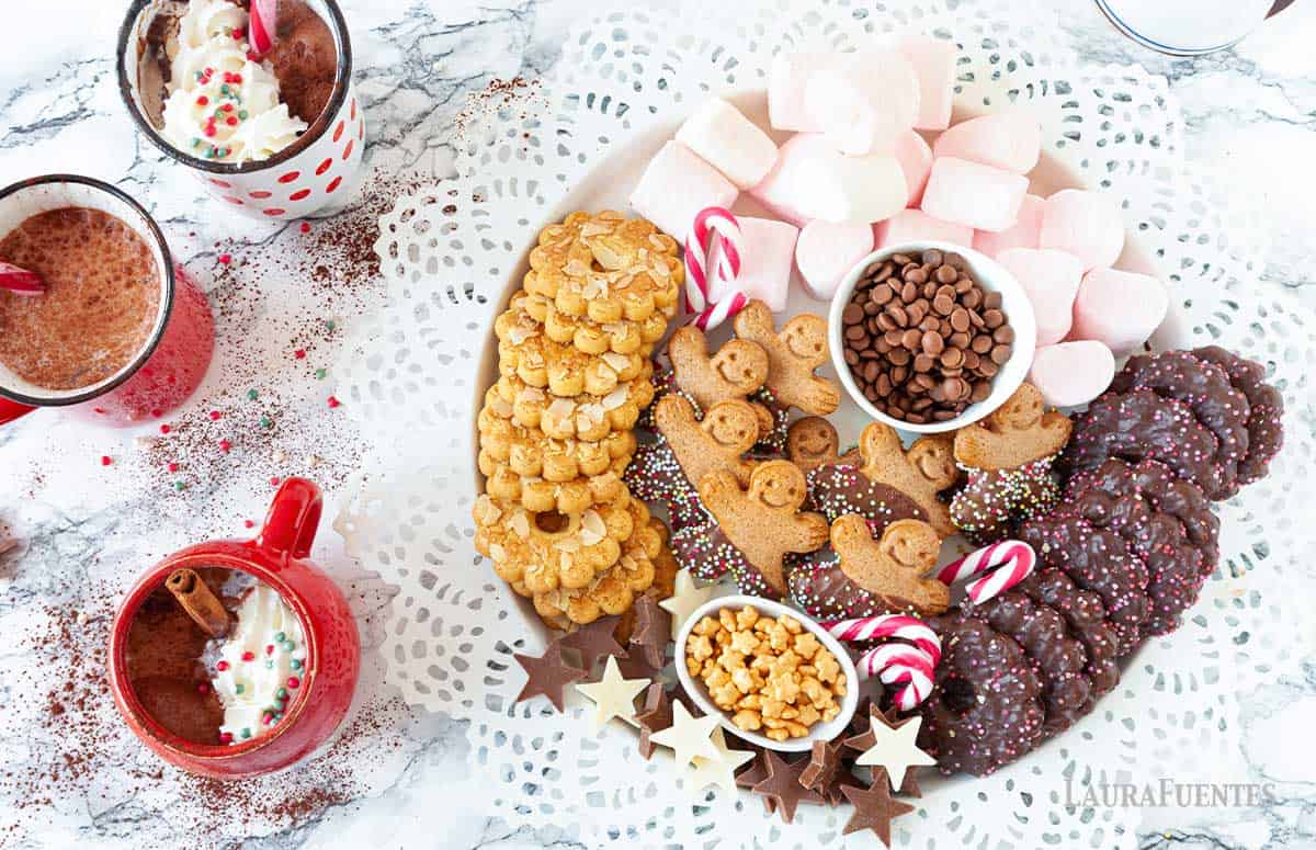 A round charcuterie board with Christmas cookies, sweets, and marshmallows.