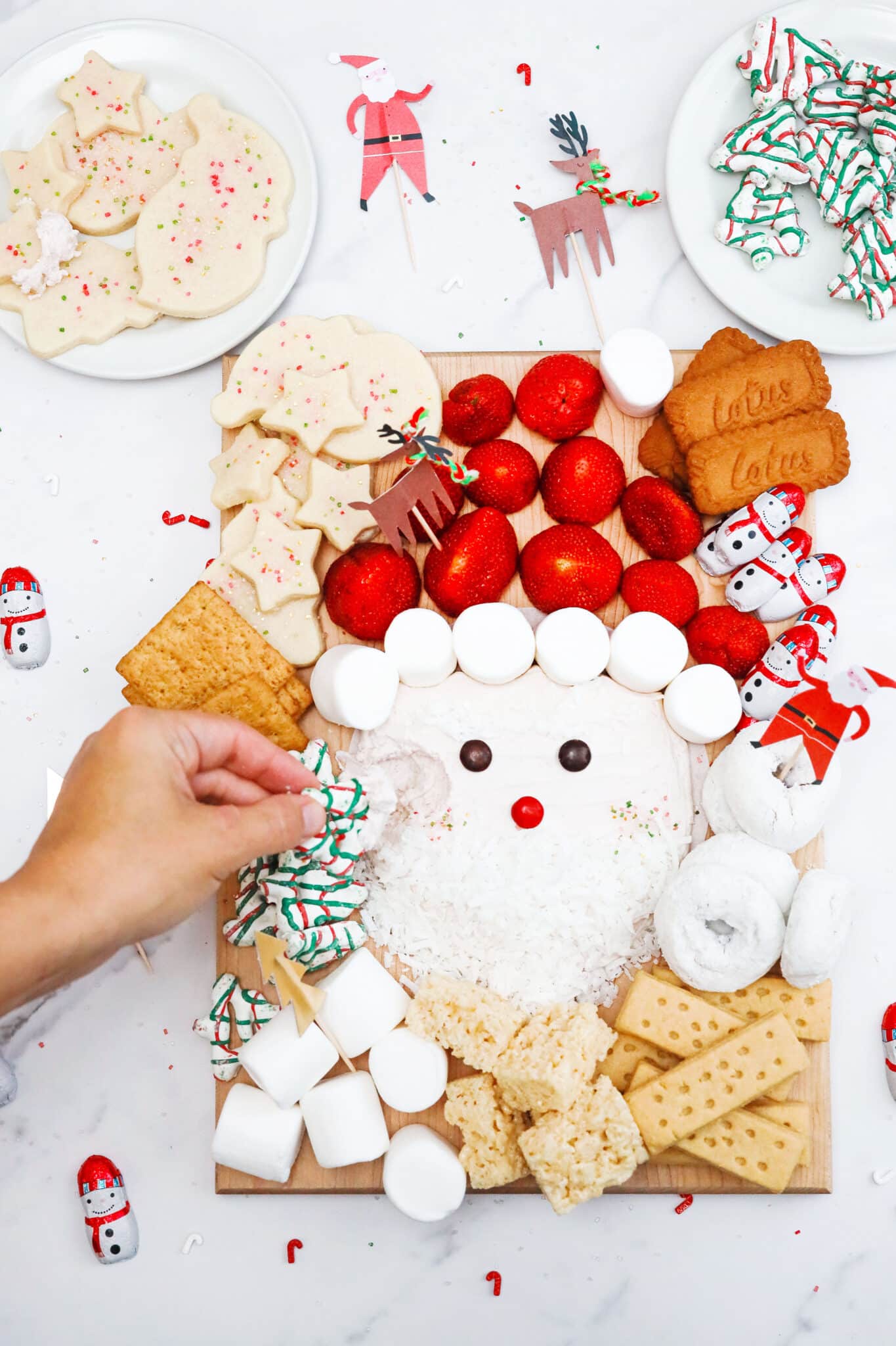 A Santa-themed Christmas dessert charcuterie board with white dip, marshmallows and strawberries.