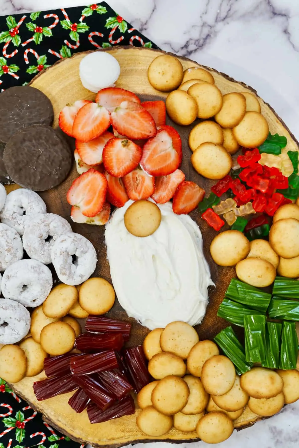 A gnome charcuterie board made from cheesecake dip, cookies, strawberries, donuts, and red and white candies.