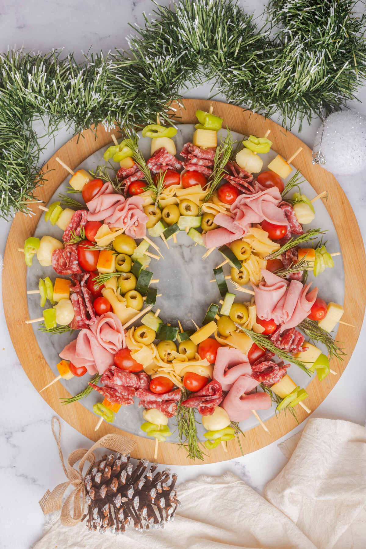 Charcuterie skewers in the shape of a Christmas wreath on a wood serving platter.